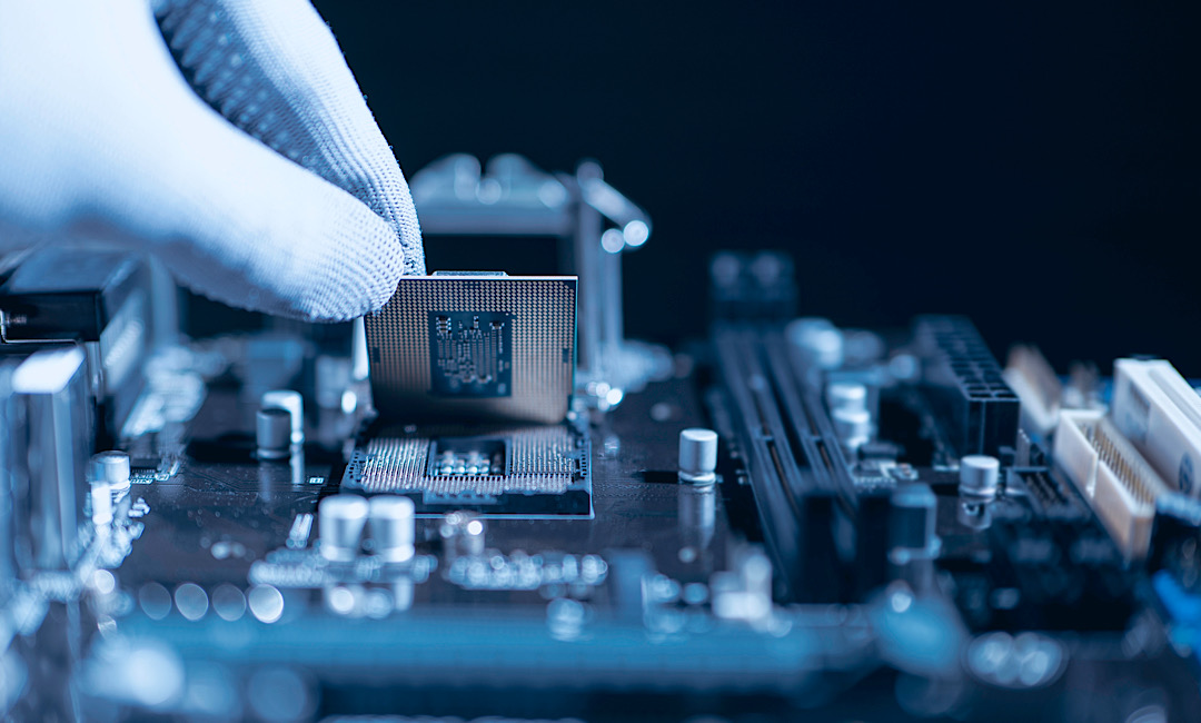 Technician installing semiconductor processor onto PCB during domestic electronics manufacturing and embedded systems assembly